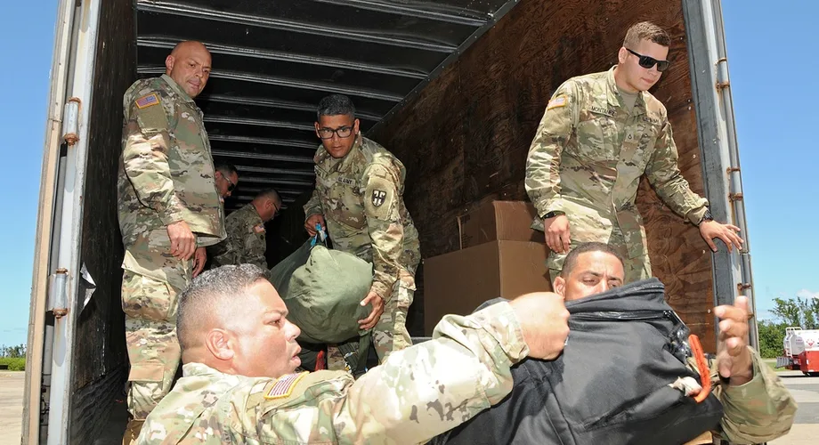 Soldiers loading duffel bags and household boxes into a truck during a PCS move