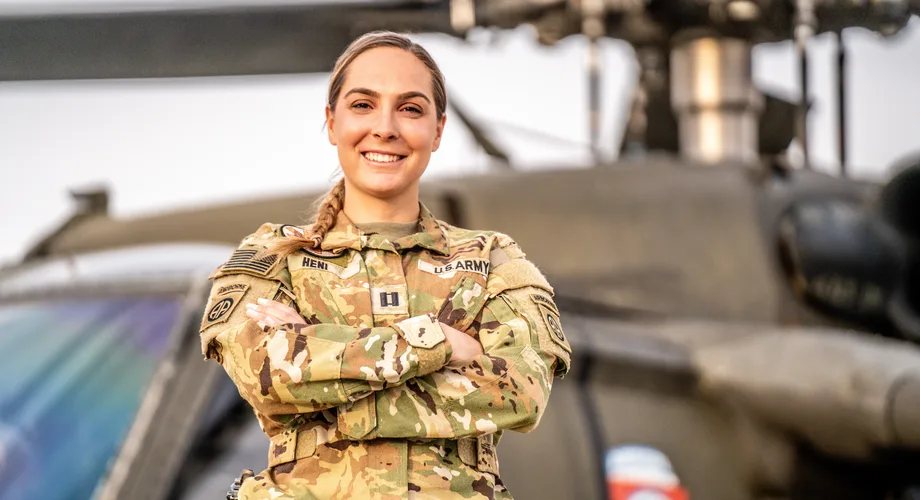 U.S. Army Capt. Annelies Heni in uniform, smiling beside a helicopter, 2024