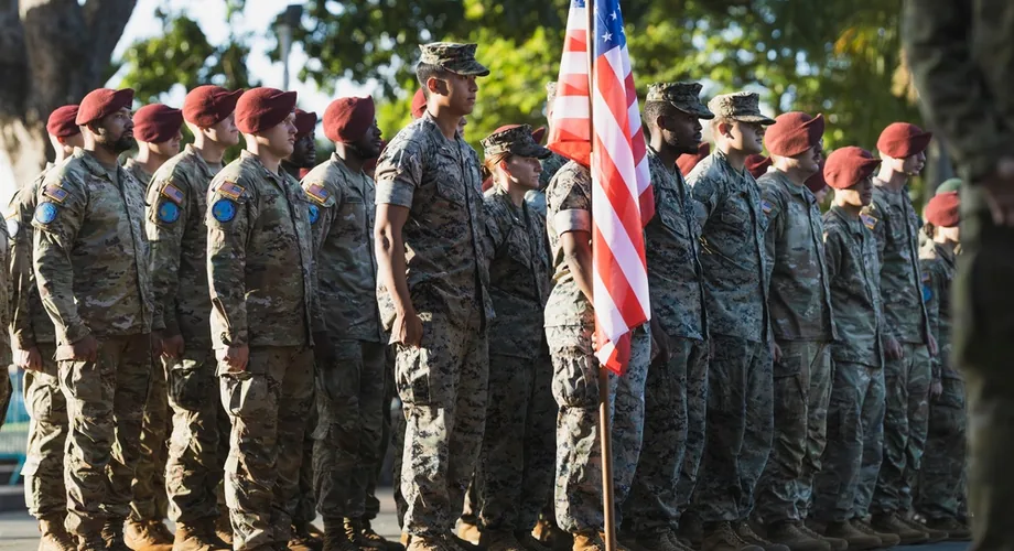 U.S. Marines and Army soldiers standing in formation with the American flag during a multinational exercise closing ceremony