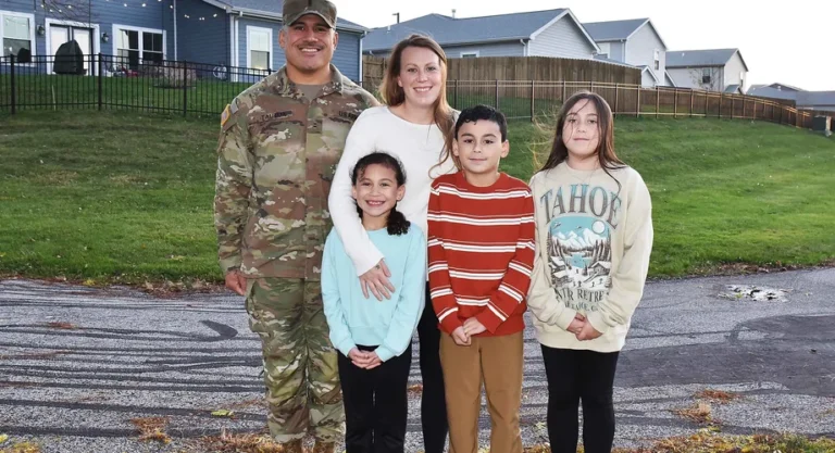 U.S. Army soldier and his family standing in front of their military housing home